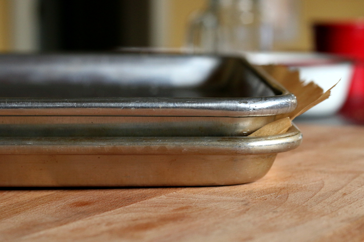 Use parchment paper and a baking sheet to evenly press the granola in the baking sheet. AlmondCherryCacaoGranolaBarsPress