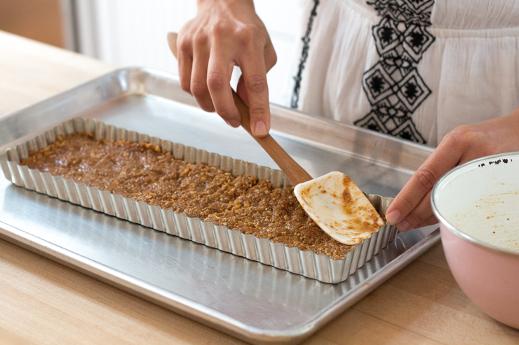 Evenly press the pretzel crust mixture into a loose bottom tart pan using the back of a spatula.