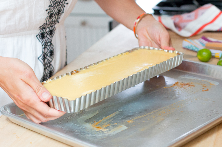 Carefully pop the key lime tequila tart out of the pan by pushing the removable bottom up.