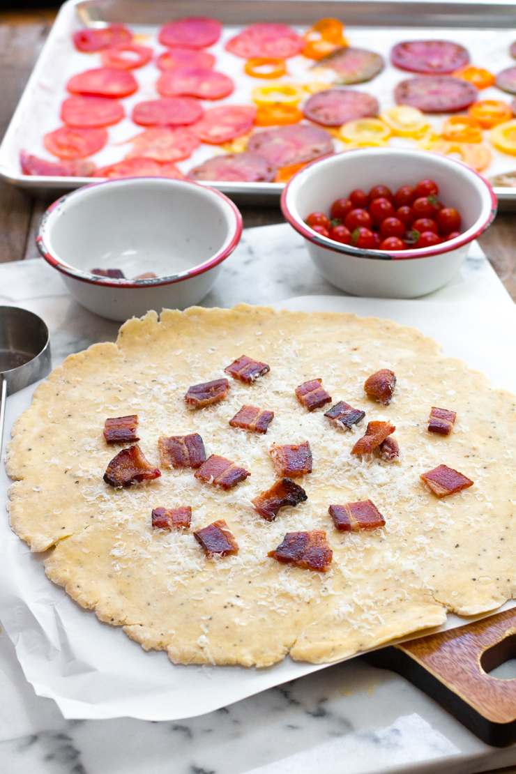 BLT Galette assembly. Bacon chopped up and sprinkled on the dough with grated pecorino cheese