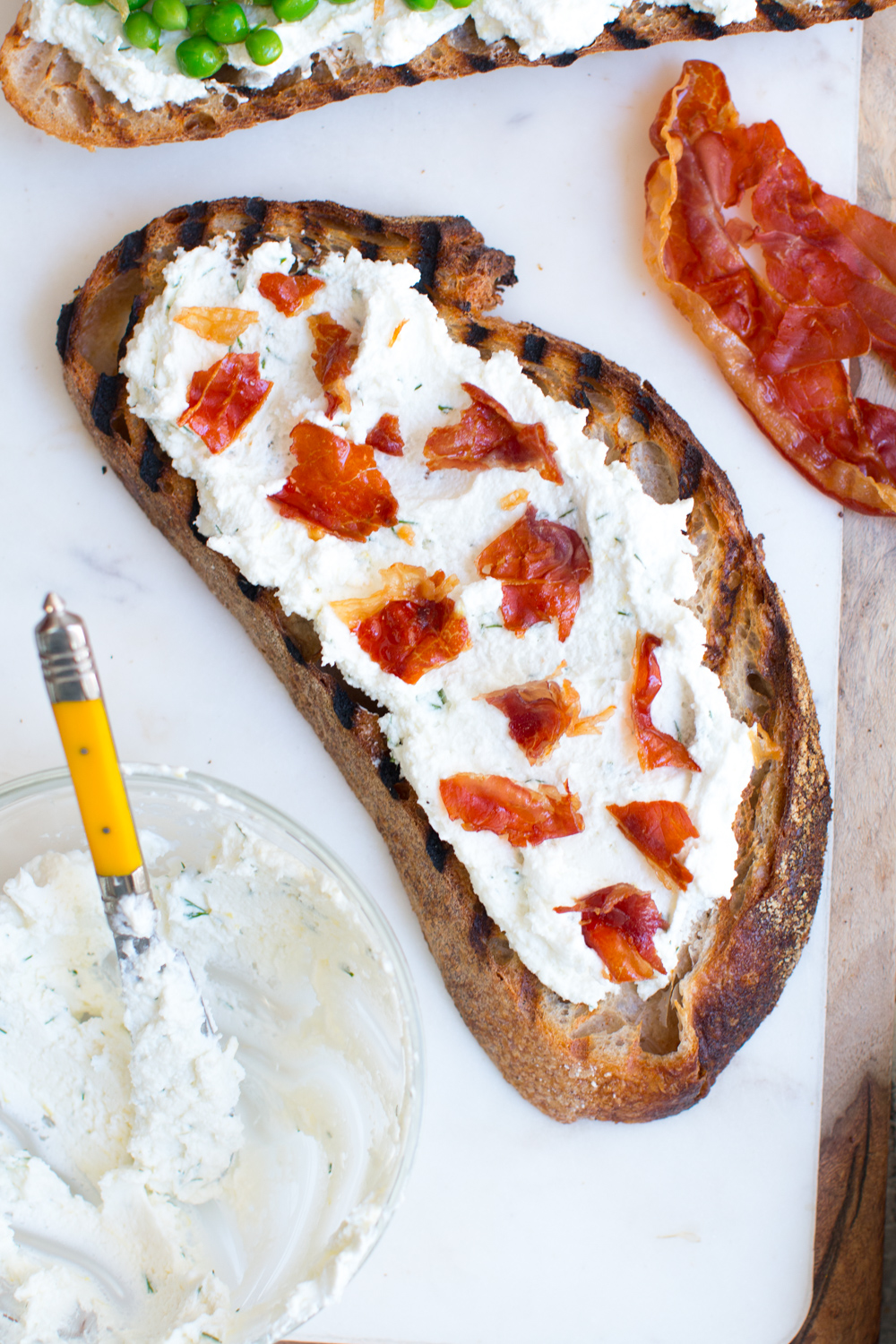 grilled Gjusta sourdough with goat cheese spread and crispy prosciutto