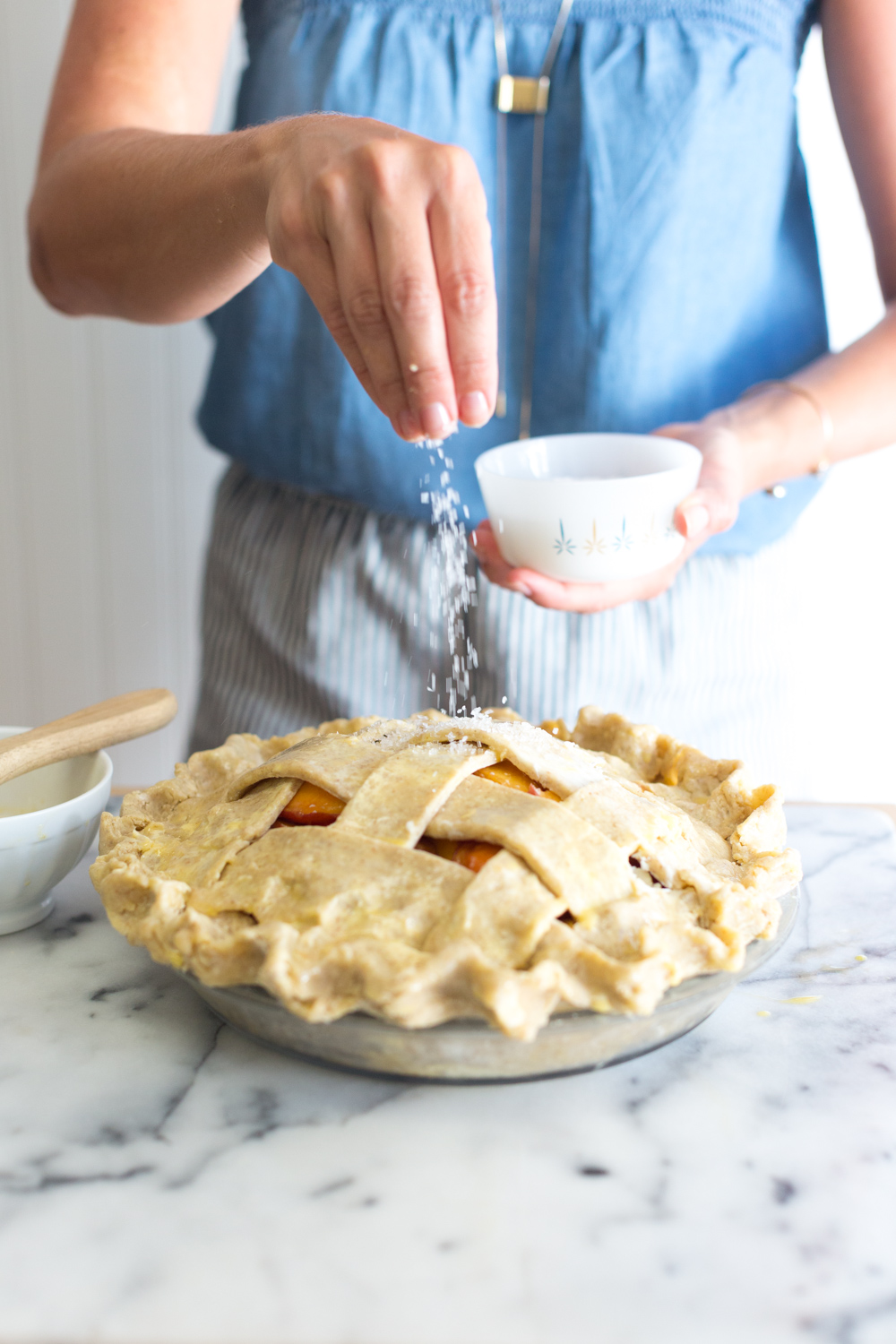 A baker sprinkles the top of the Rye Rye Peach Pie with sparkling sugar.