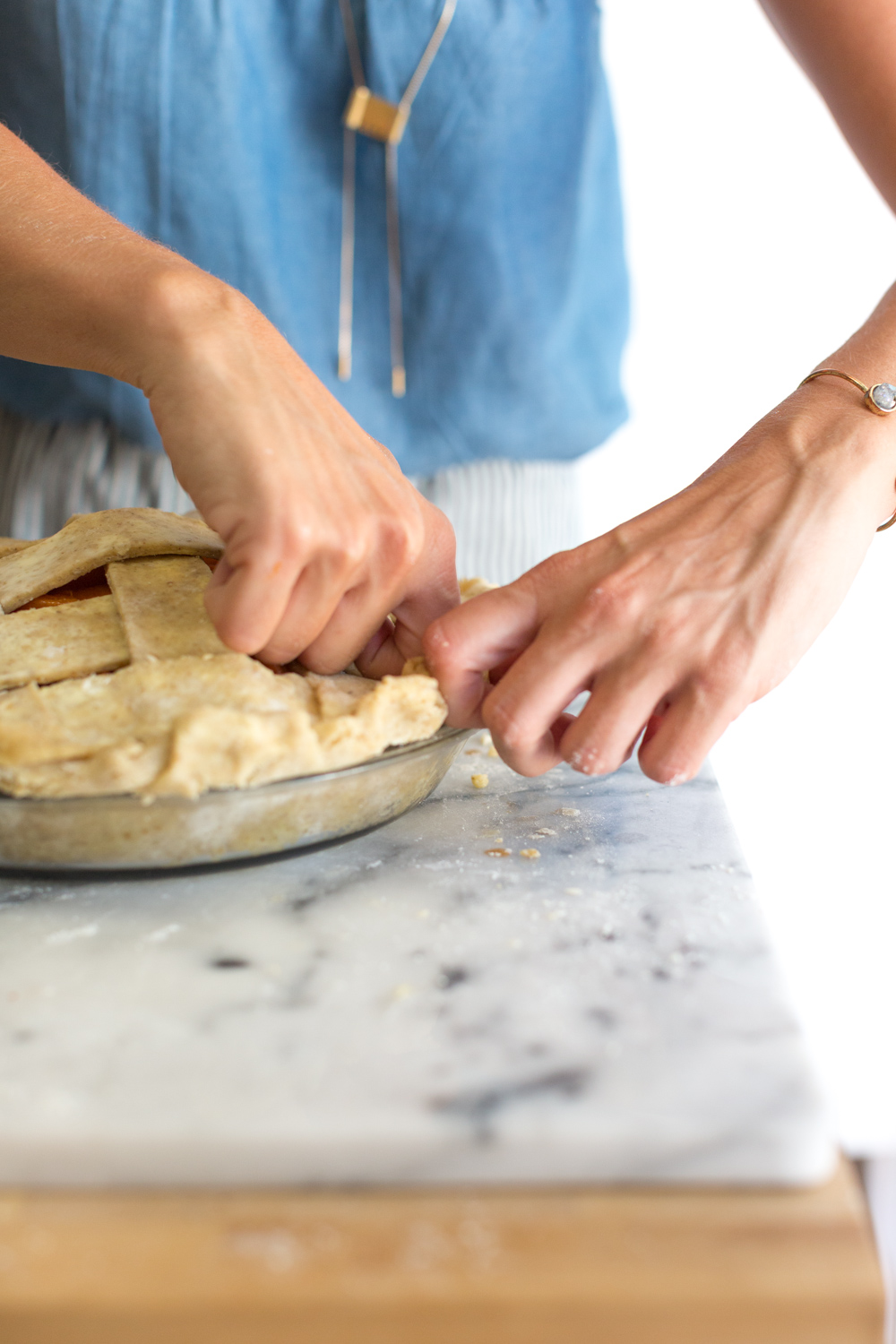 A baker shows how to flute the edge of a pie crust.