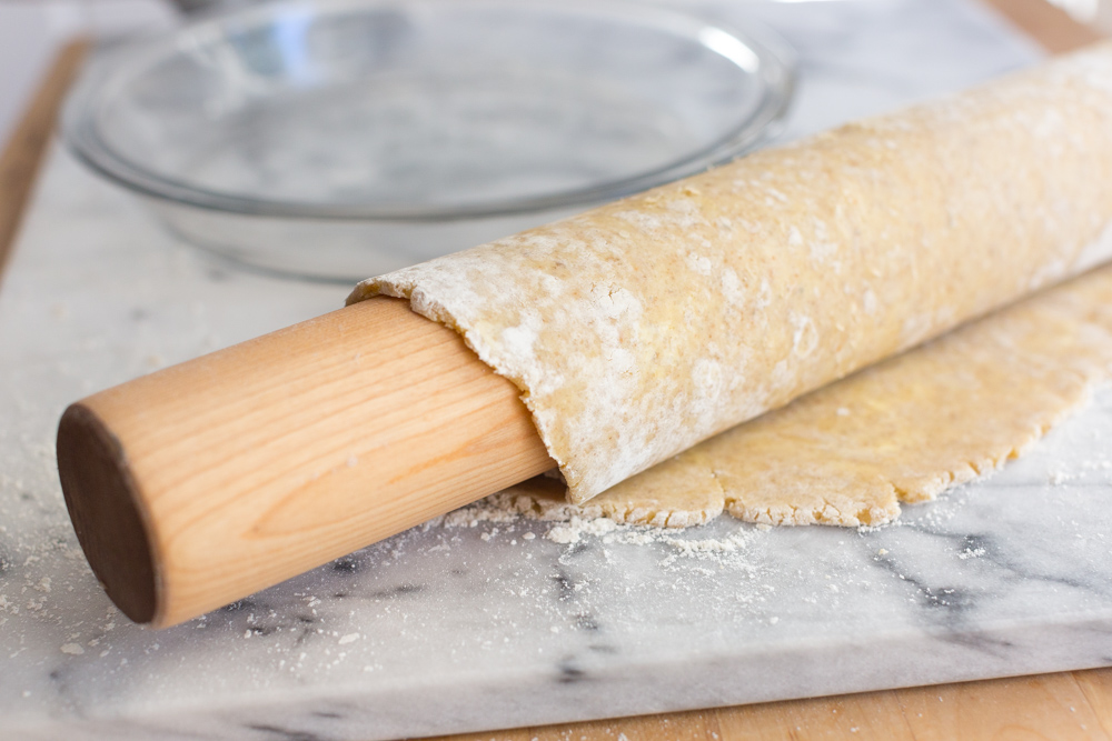 transferring pie dough to a pie dish with a rolling pin