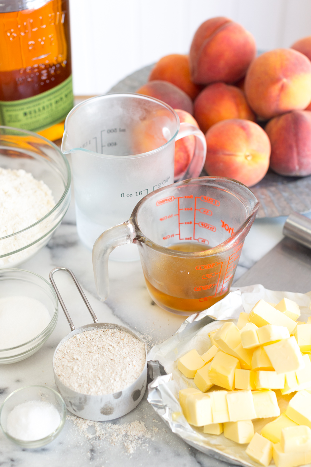 Ice cold ingredients for rye flour pie dough. Butter, rye whiskey, rye flour, peaches.