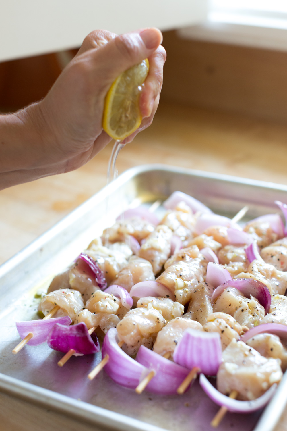 Squeeze lemon juice over the feta brined chicken skewers.