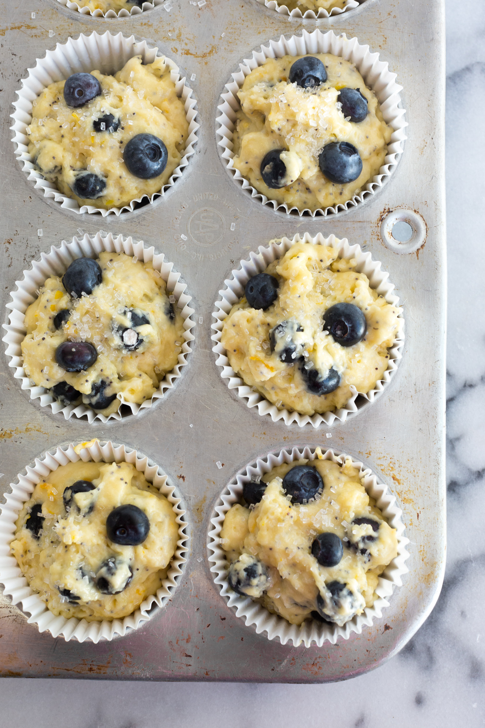 Muffin tin filled with Blueberry Lemon Poppy Seed Muffin batter.