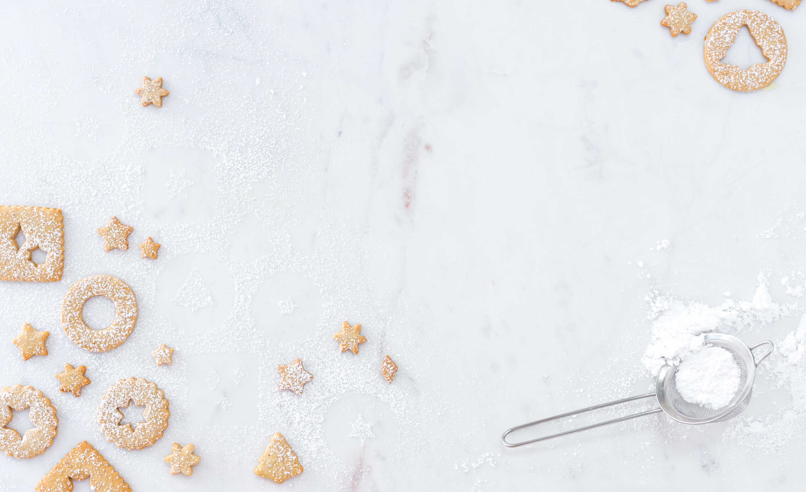 Linzer cookies at the edges of a white marble background