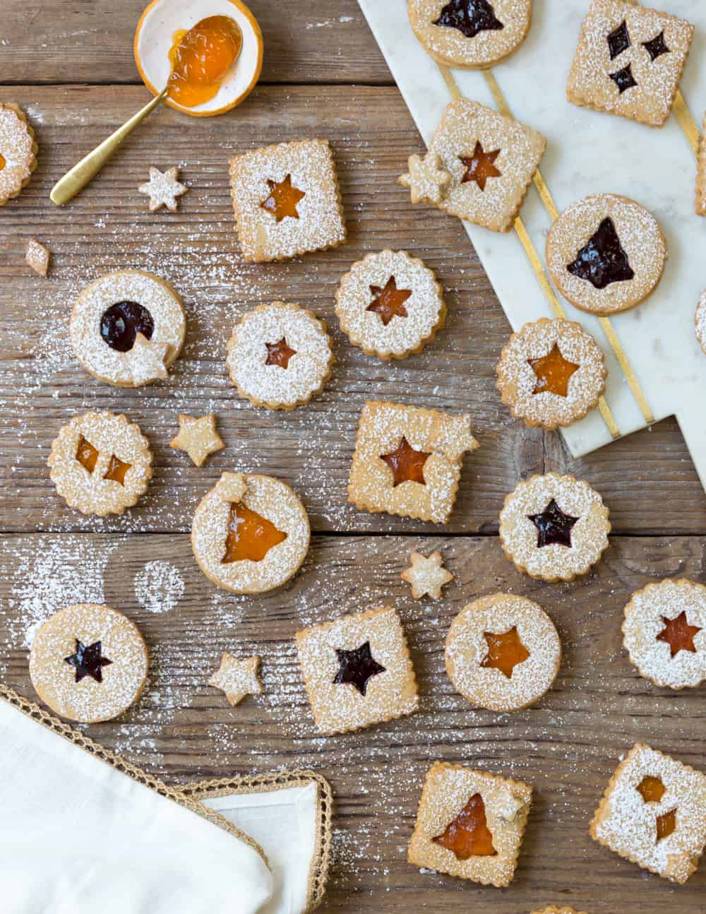 Hazelnut Linzer Cookies with Wine Jam displayed on a wood background and sprinkled with powdered sugar