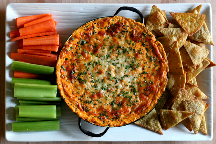 Spicy White Bean Buffalo Dip with baked lime tortilla chips and veggie sticks.