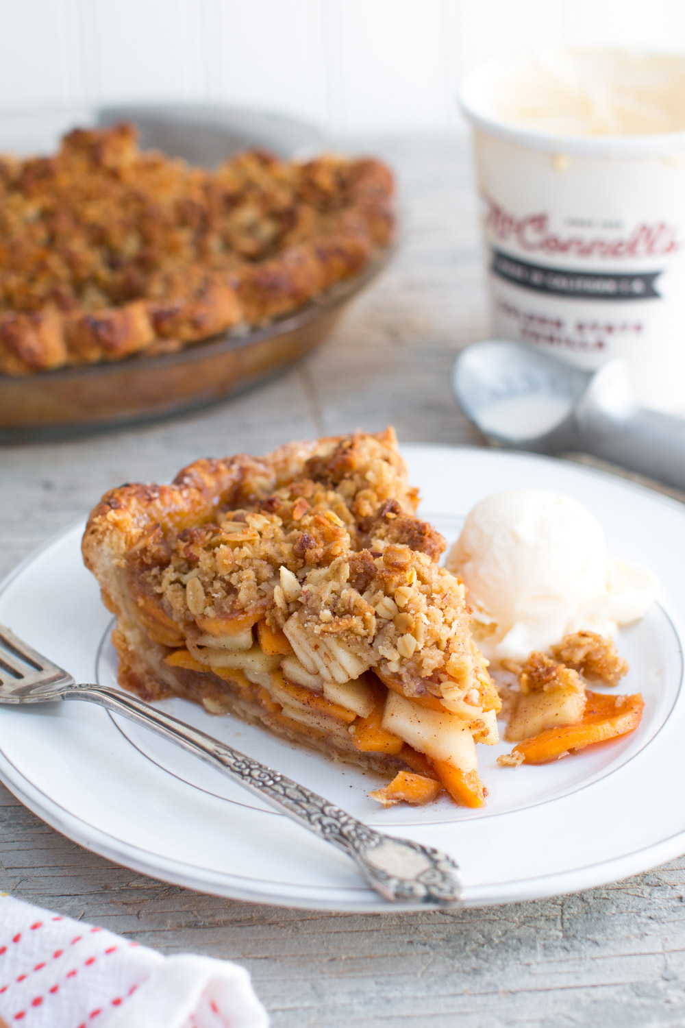 Apple Persimmon Crumble Pie slice with ice cream on a white plate