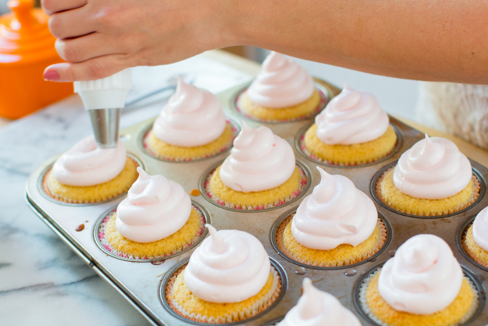 thick swirls of pink meringue are piped onto the top of the baked cupcakes