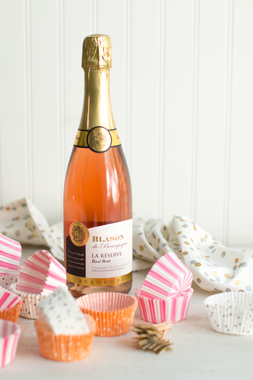 a bottle of pink champagne placed among pink cupcake wrappers