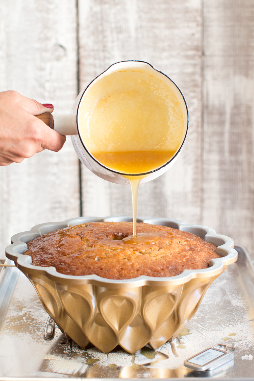pouring bourbon glaze over the bottom of the bundt cake