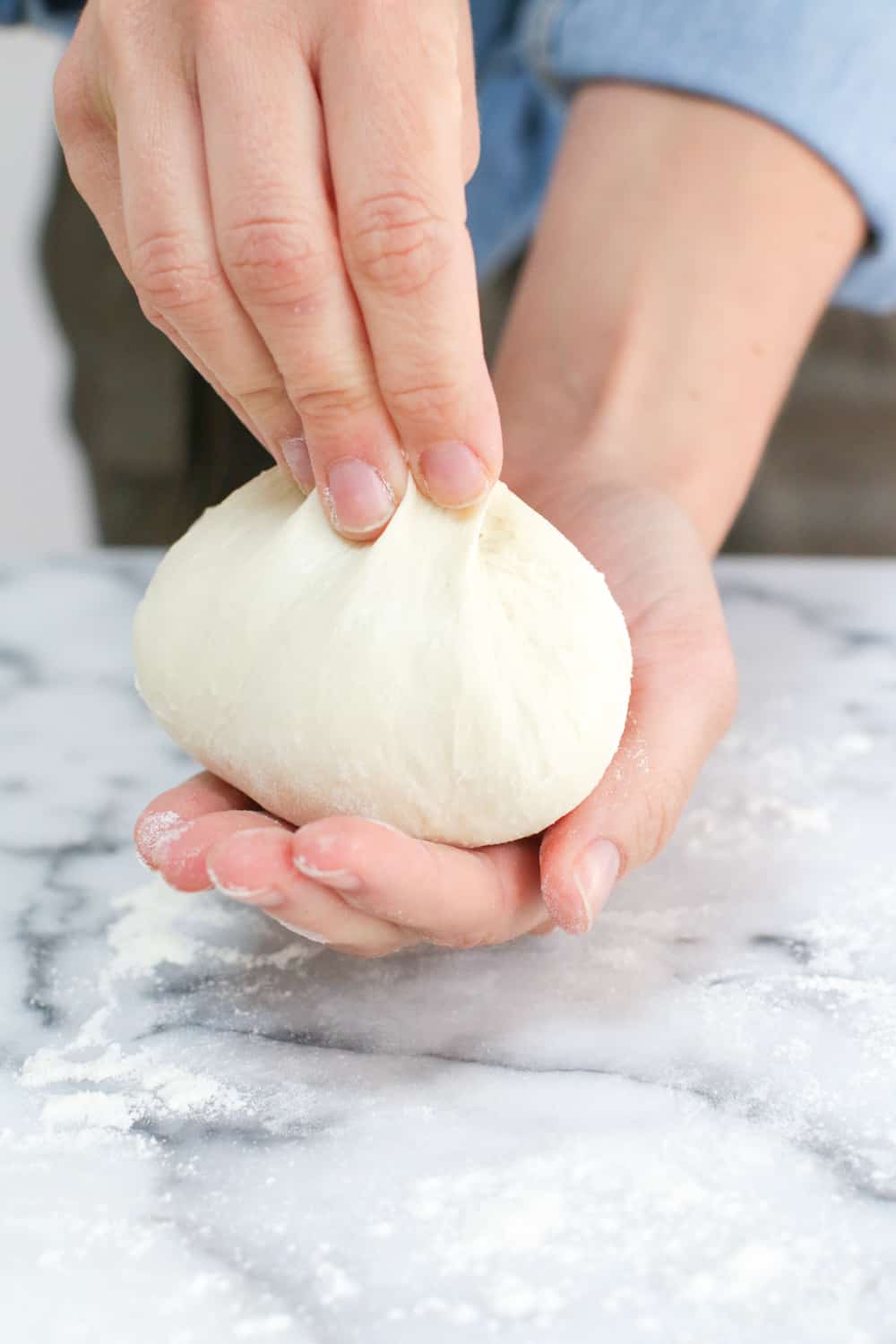 pinching the top of the pizza dough ball