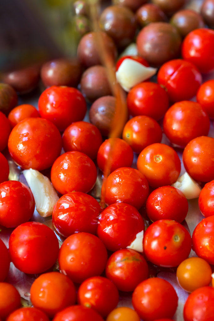 adding olive oil to cherry tomatoes for confit
