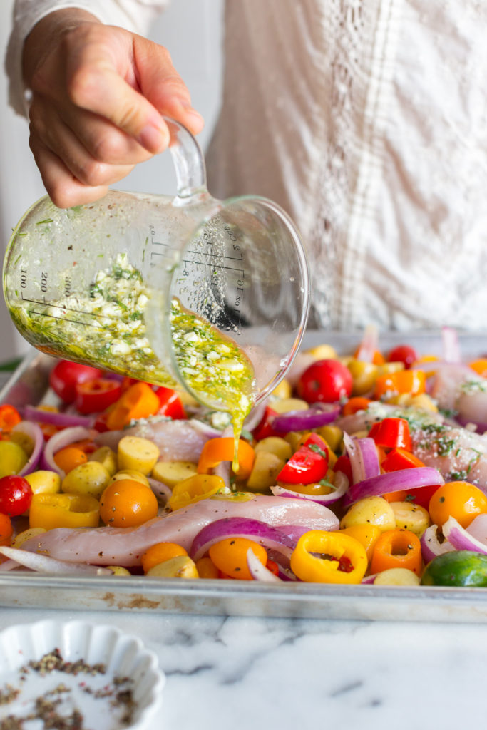 Adding marinade to the Herby Feta Lemon Chicken and Veggie Sheet Pan Dinner