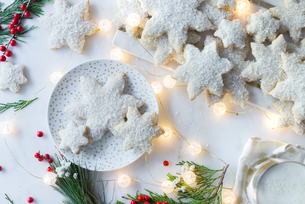 Spiced Coconut Snowflake Sugar Cookies shot overhead with holiday lights on marble background