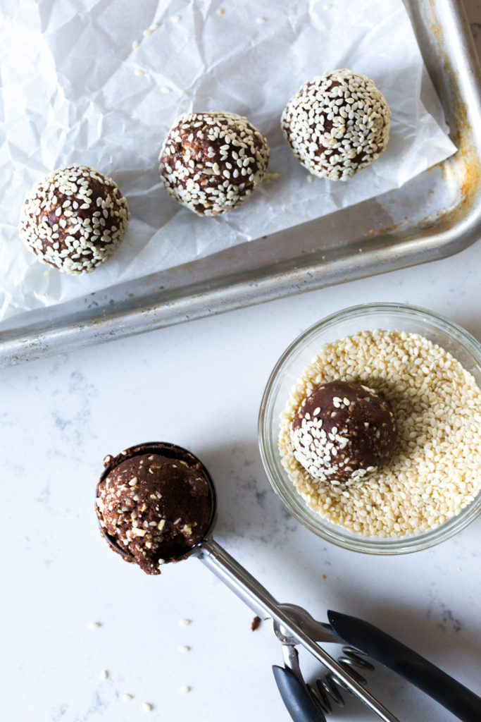 Rolling Cashew Date Chocolate Balls in sesame seeds