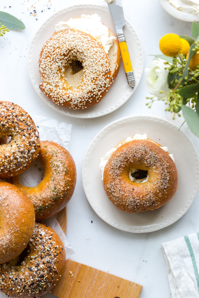 a pile of bagels, one with cream cheese