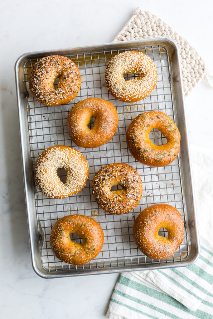 an assortment of bagels cooling on a baking sheet
