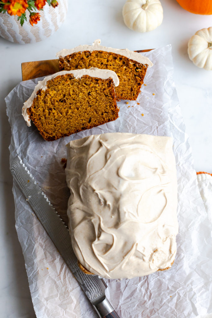 Slicing Pumpkin Spice Bread with Maple Cream Cheese Frosting