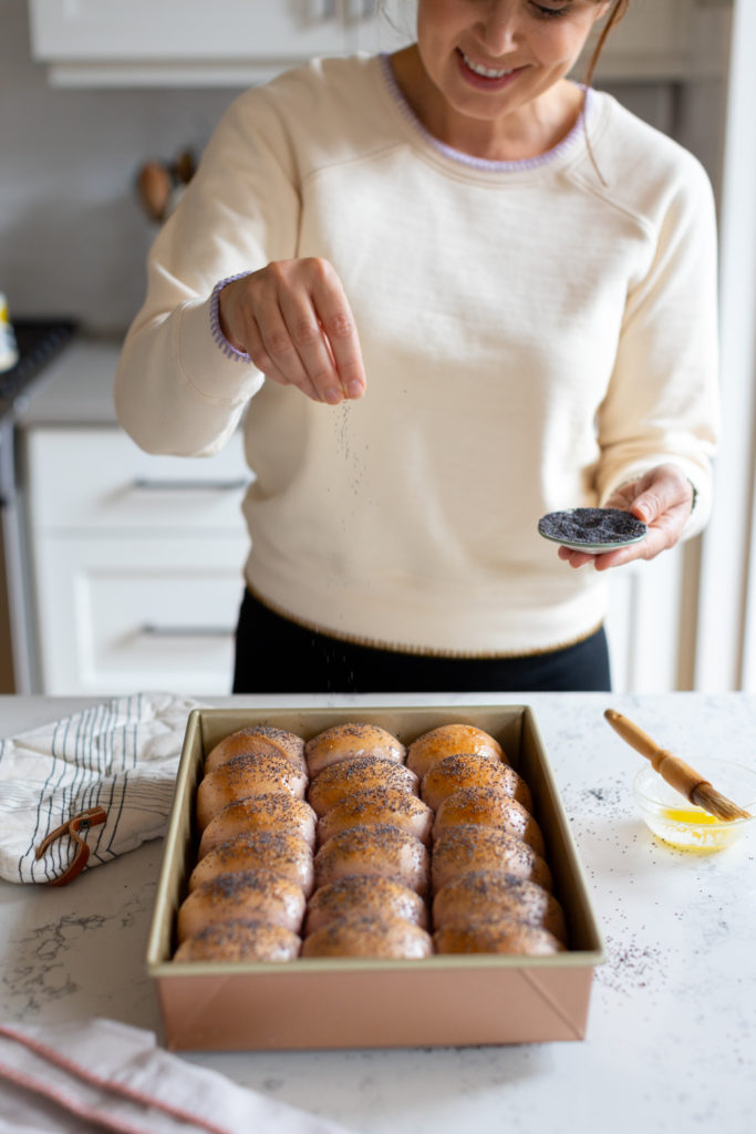 adding poppy seeds to warm dinner rolls