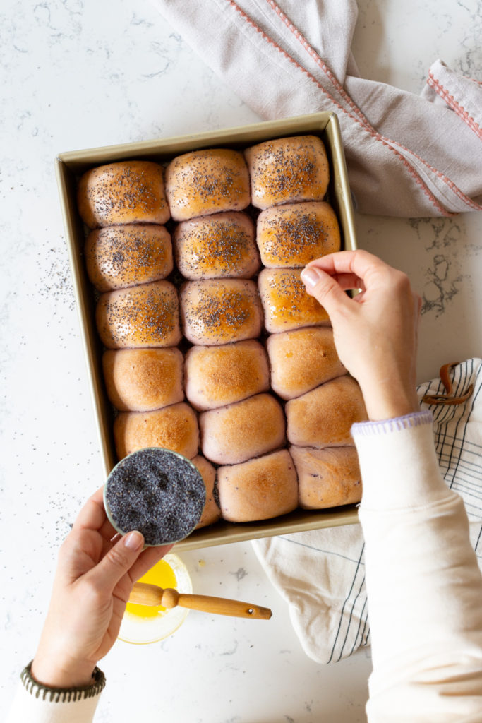 adding poppy seeds to warm dinner rolls
