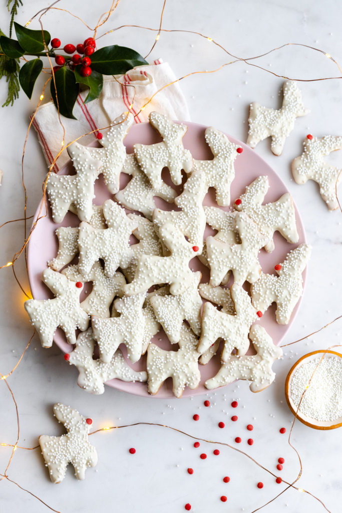 Pink plate full of Reindeer Animal Cookies among fairy lights on a marble surface