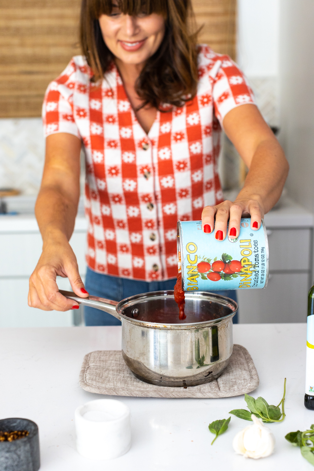 adding crushed tomatoes to pizza sauce