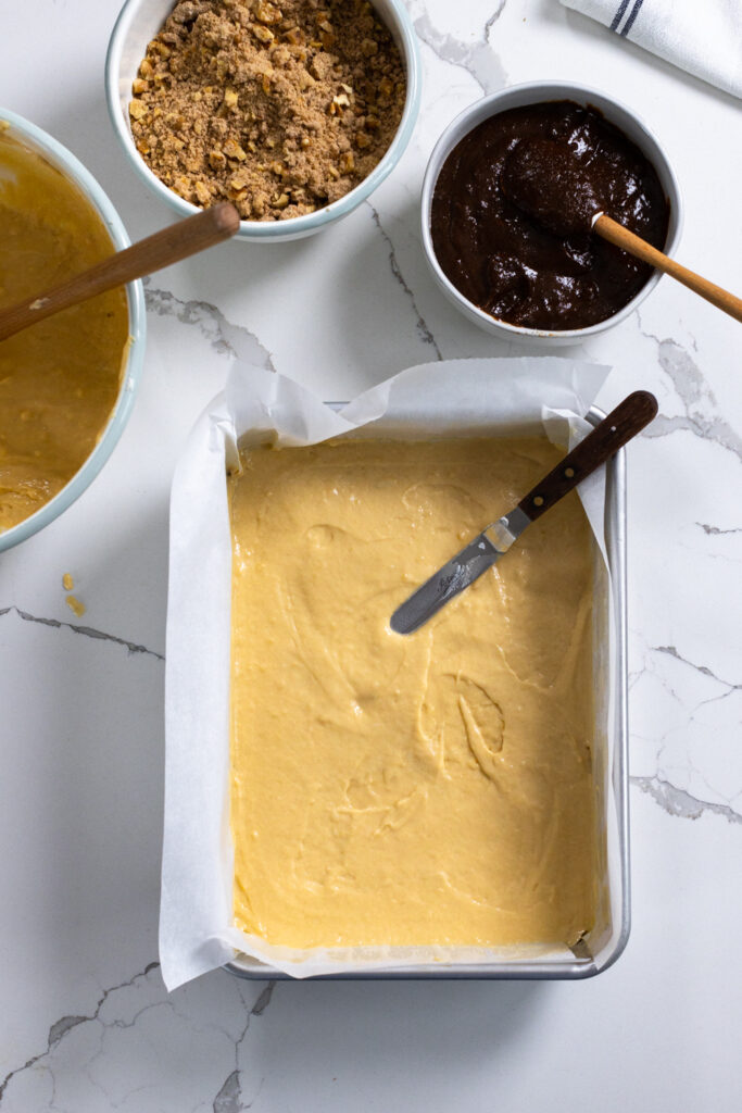 Step 1 is spreading half of the coffee cake batter in a lined cake pan