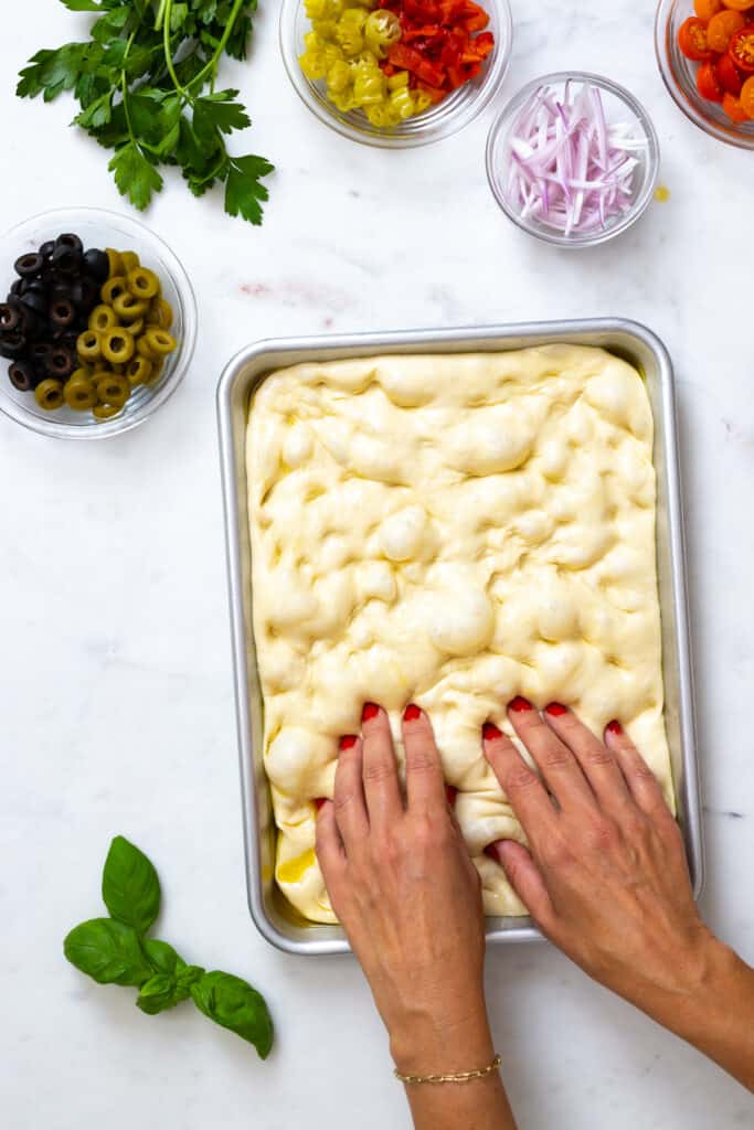Dimpling focaccia dough with fingers