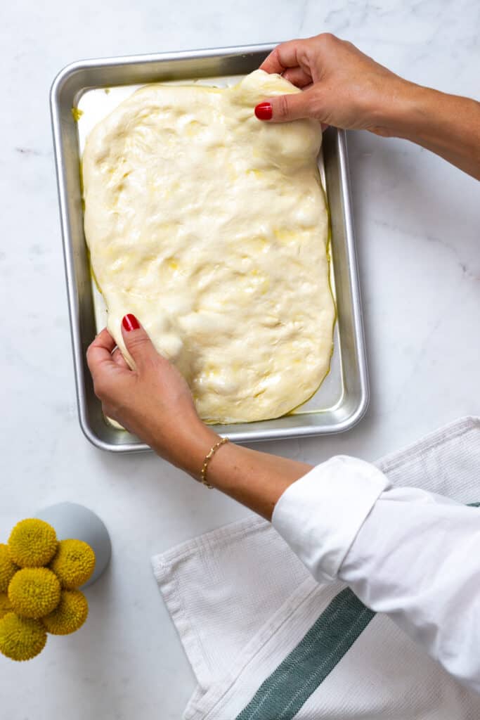 stretching Focaccia dough in the baking sheet