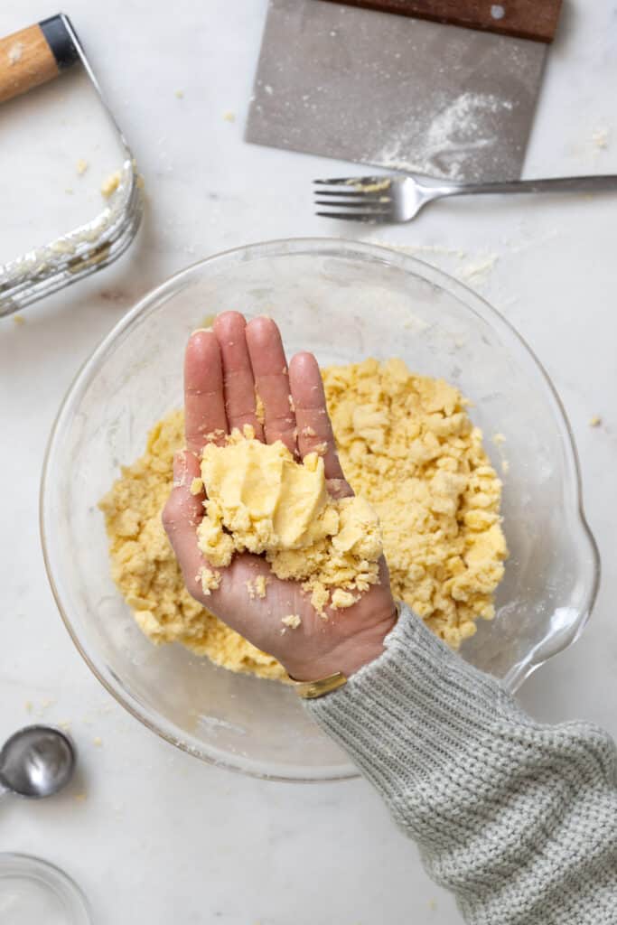 Pie dough squeeze test step 3 - open hand shows dough has held it shape after being squeezed - finger and palm impressions remain