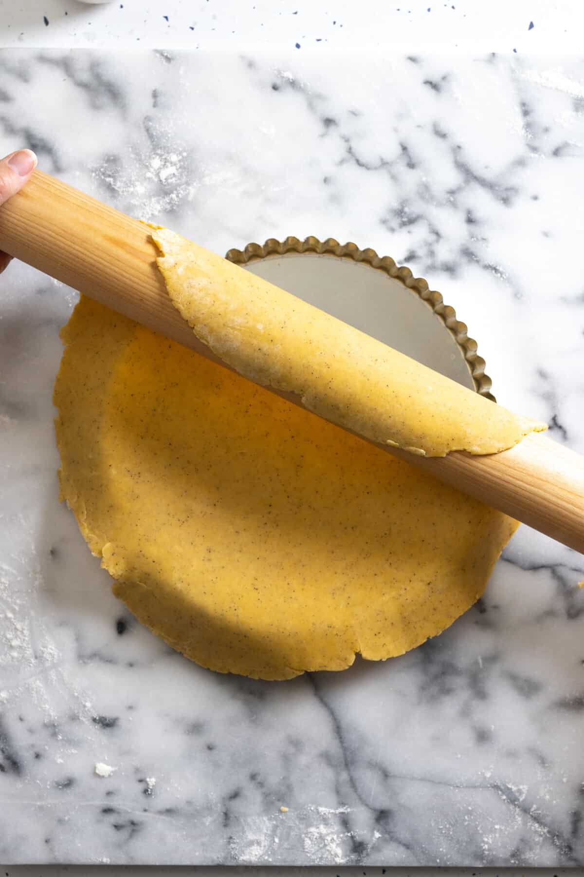 unrolling tart dough into pan