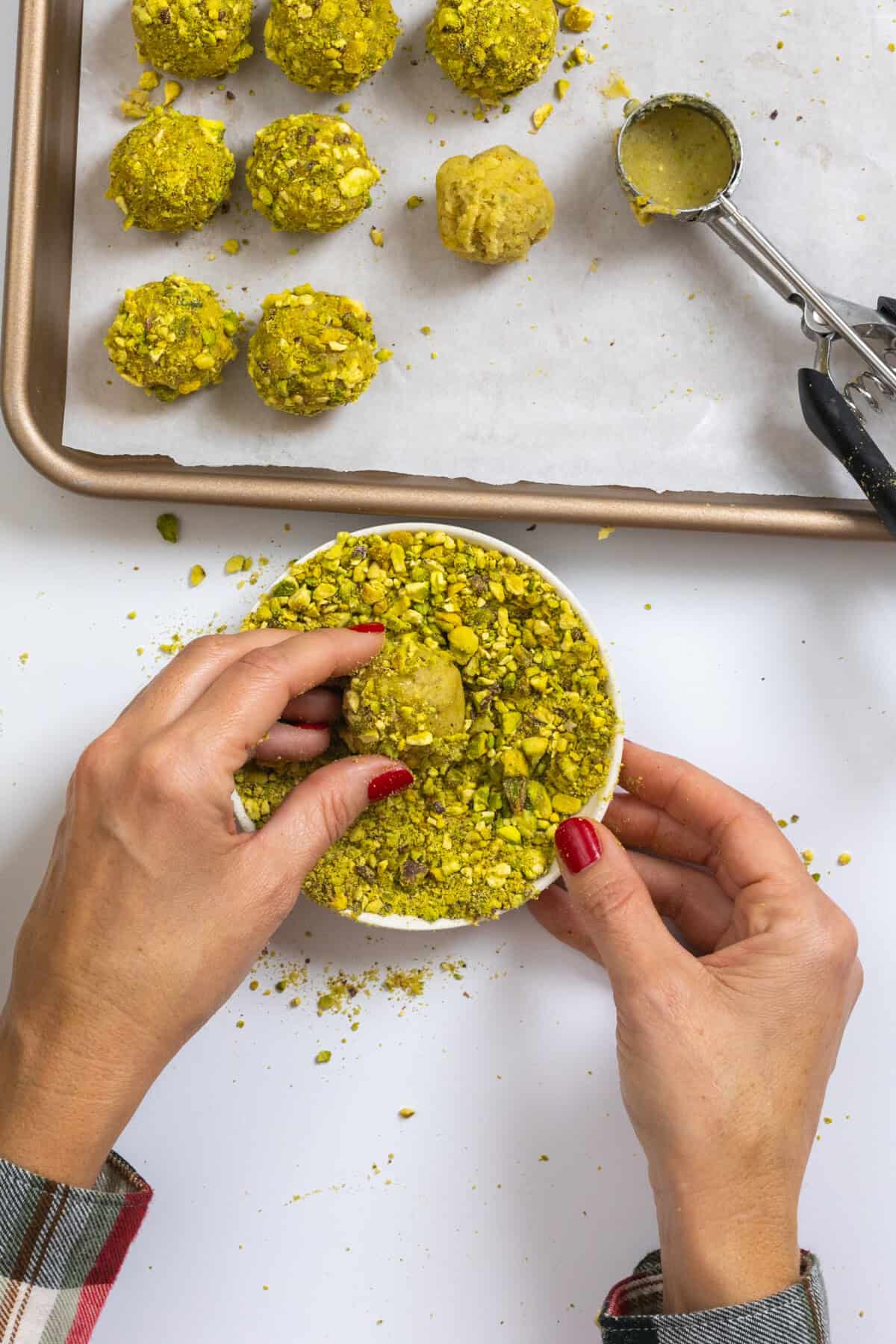 Rolling cookie dough balls in chopped pistachios