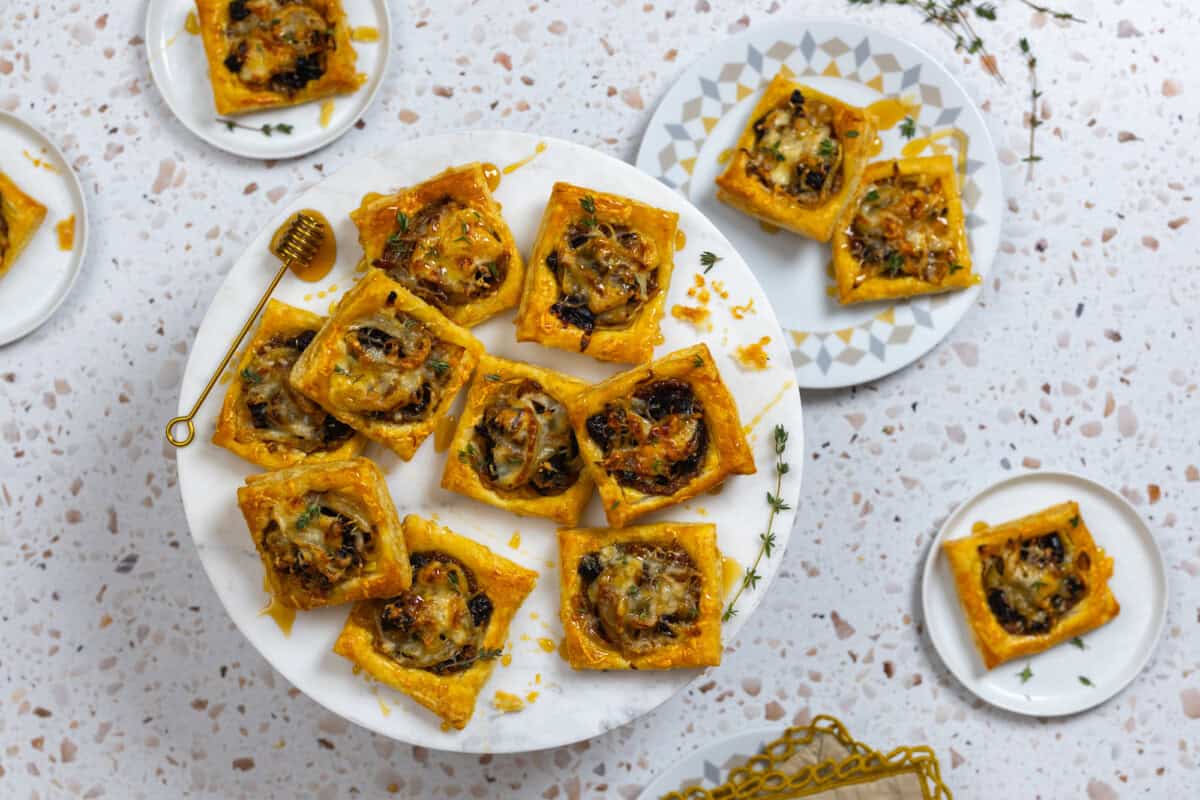 Prune Onion Fontina Puff Pastry Tarts ready to party - overhead arranged and styled on a marble stand