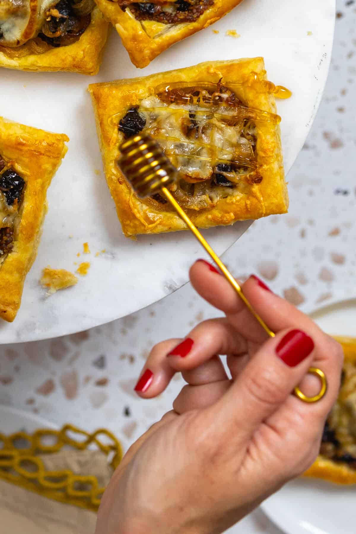 drizzling the prune onion cheese tarts with honey - close up