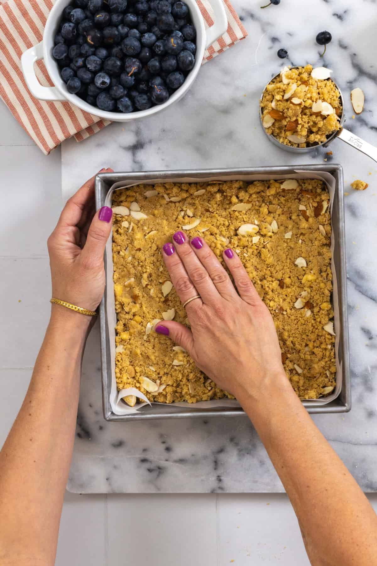 pressing almond crumble shortbread into a crust