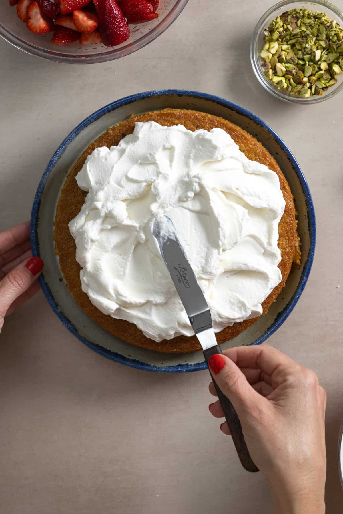 adding whipped cream topping to olive oil cake