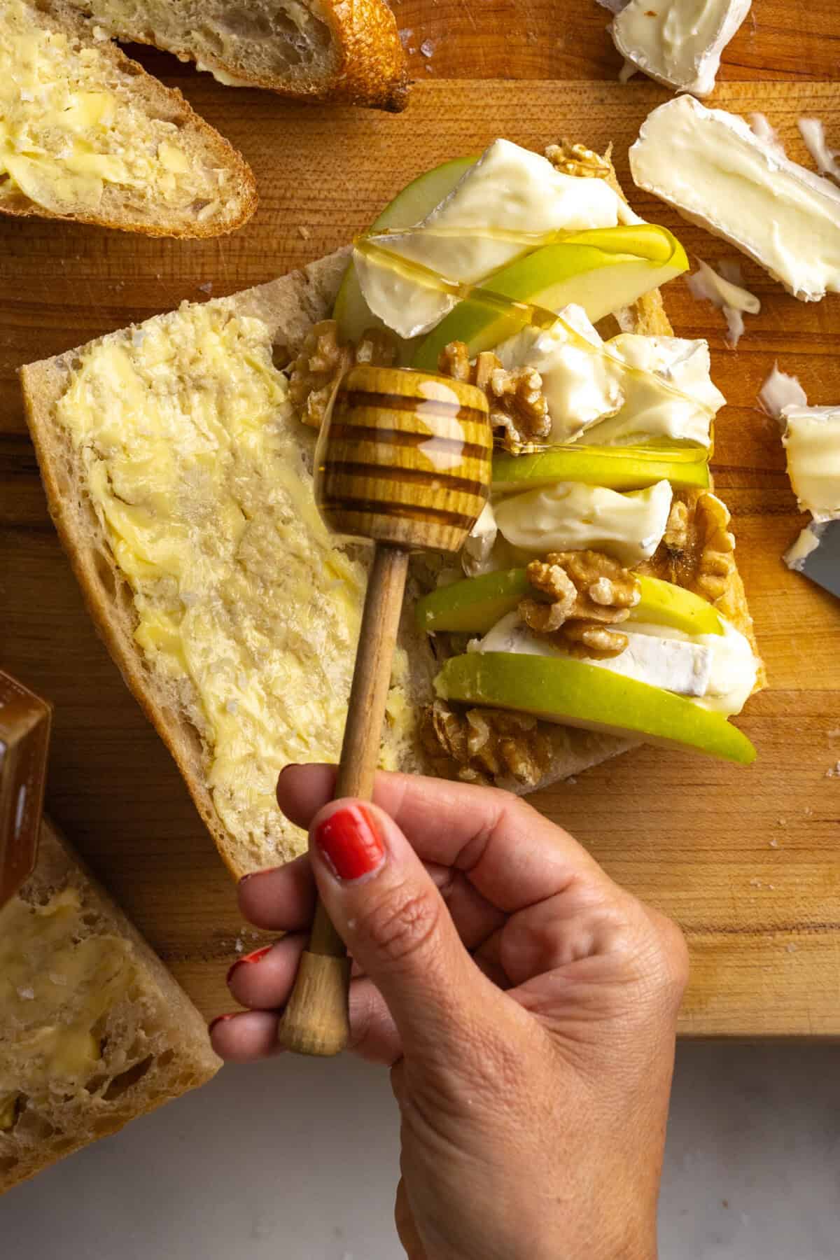 Drizzling honey onto baguette sandwiches