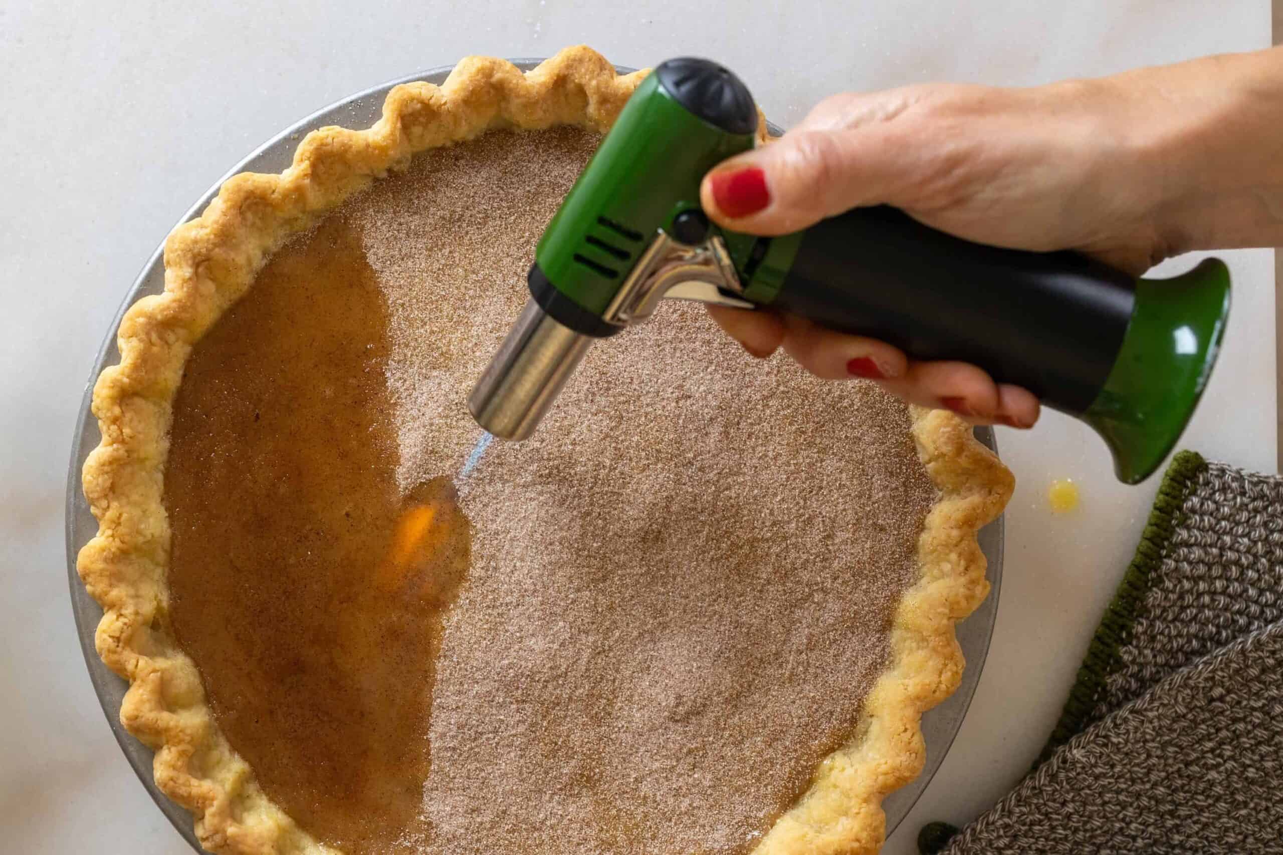 Using a torch to brulee the top of the pie