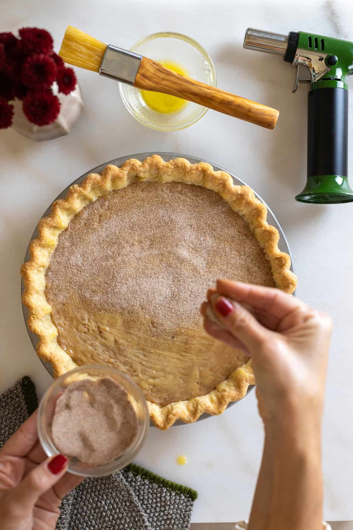 Sprinkling cinnamon sugar over pie filling