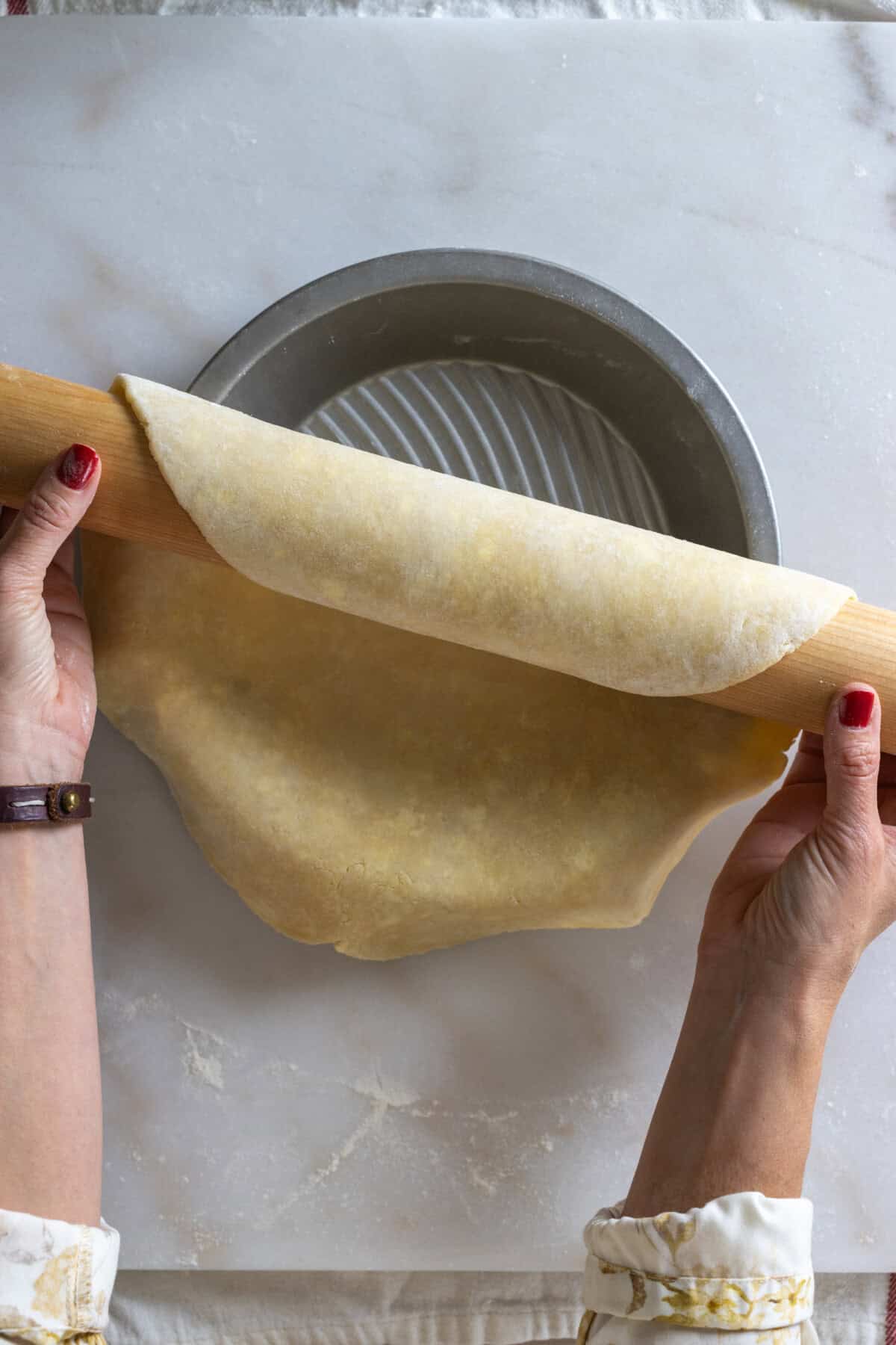 Unrolling pie dough into pie dish
