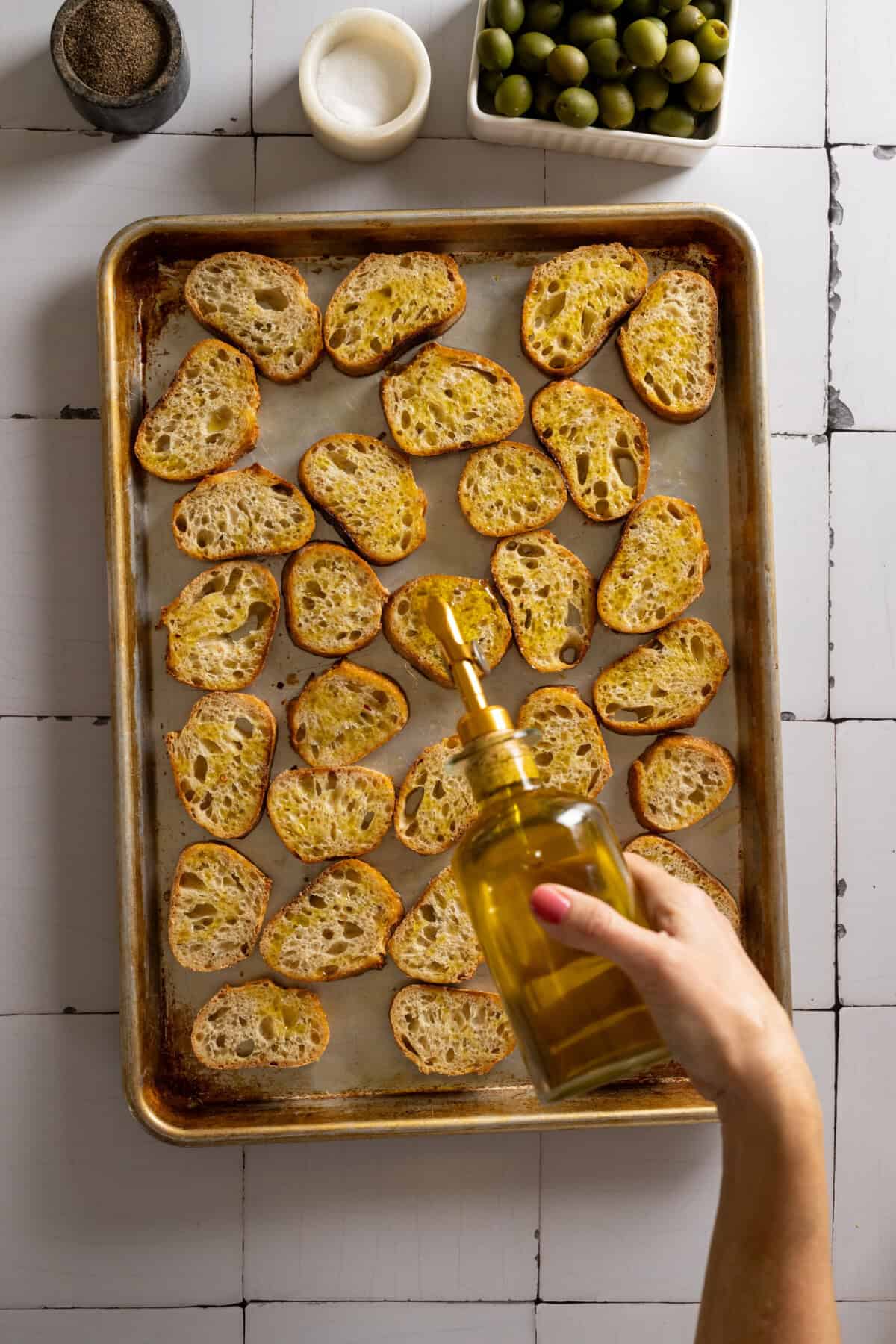 Adding olive oil to sliced baguette